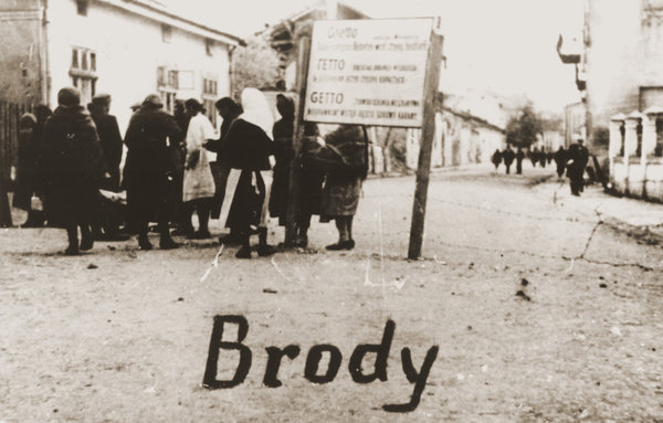 A group of Jewish women at the entrance to the Brody Ghetto in Eastern Galicia, 1942. The sign is written in German, Ukrainian and Polish. (United States Holocaust Memorial Museum / Collection of Eugenia Hochberg Lanceter)