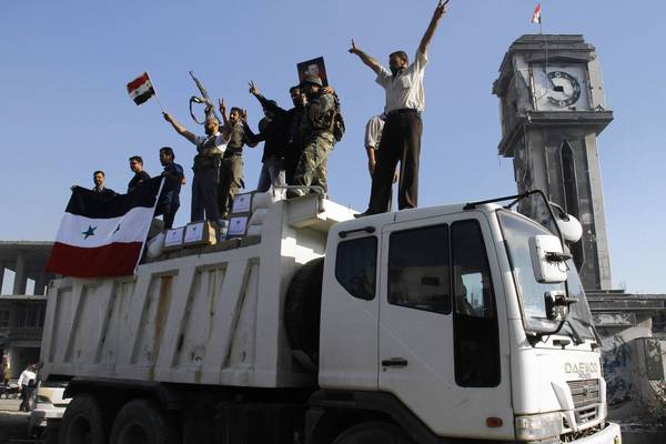 Forces loyal to the Syrian army celebrate as they drive through the main square of Qusair after helping President Bashar Assad's soldiers retake control of the area this month. (AFP/Getty Images / June 5, 2013)