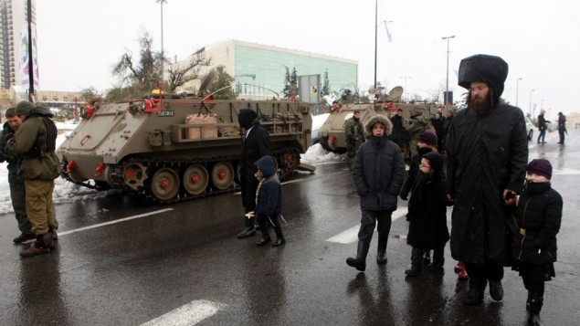 Israeli soldiers and emergency workers drive on armored personnel carriers in Jerusalem December 14, 2013. Jerusalem's heaviest snow for 50 years forced Israeli authorities to lift a Jewish Sabbath public transport ban on Saturday and allow trains out of the city where highways were shut to traffic. Troops in armored vehicles were helping emergency services crews to try to restore electricity for thousands in the Jerusalem area. (Photo credit: Yossi Zamir/Flash90)
