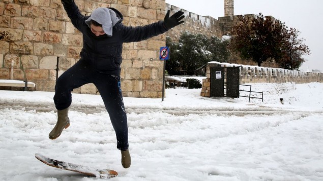 A young boy snowboards at Jaffa Gate outside the Old City of Jerusalem, on the third day of the major snowstorm that hit the capital, Saturday, December 14, 2013. (photo credit: Hadas Parush/Flash 90)