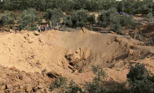 Palestinian boys look at a crater which police said was caused by an Israeli air strike in the central Gaza Strip July 7, 2014. // Reuters