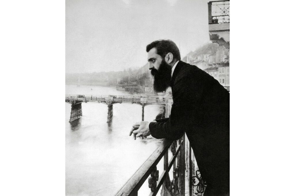 The founder of Zionism, Theodor Herzl, looks out over the Rhine River from the balcony of the hotel in Basel, Switzerland, where he stayed during the First Zionist Congress in 1897. Israeli historian and former diplomat Michael B. Oren defines Zionism as 'the belief that the Jewish people should have their own sovereign state in the Land of Israel.'