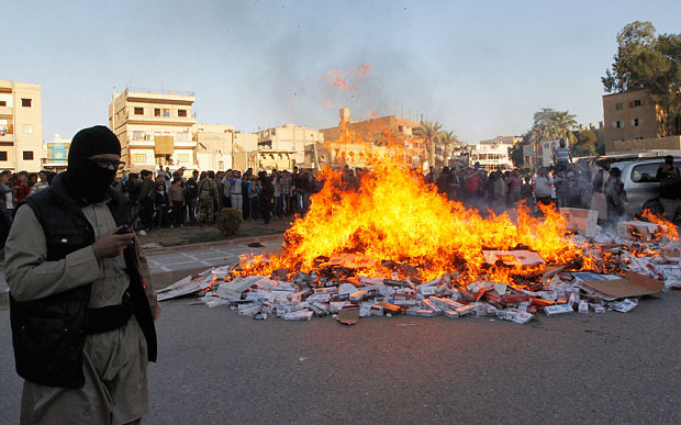 A fighter from Islamic State in Iraq and the Levant (ISIL) stands near burning confiscated cigarettes in the city of Raqqa Photo: REUTERS