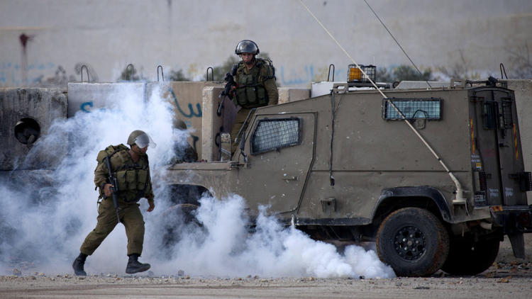 Israeli soldiers run from tear gas during clashes outside the Ofer military prison near the West Bank city of Ramallah on Nov. 18. (Majdi Mohammed / Associated Press)