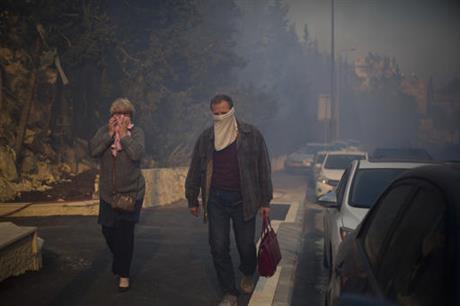 People walk a away from wildfires in Haifa, Israel, Thursday, Nov. 24, 2016. A raging wildfire ripped through parts of Israel's third-largest city on Thursday, forcing tens of thousands of people to evacuate their homes and prompting a rare call-up of hundreds of military reservists to join overstretched police and firefighters. Spreading quickly due to dry, windy weather, the fire quickly spread through Haifa's northern neighborhoods. While there were no serious injuries, several dozen people were hospitalized for smoke inhalation. (AP Photo/Ariel Schalit)