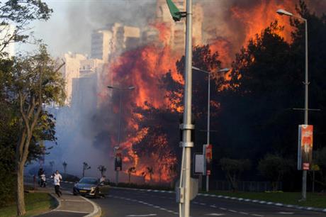 People run as wildfires rages in Haifa, Israel, Thursday, Nov. 24, 2016. A raging wildfire ripped through parts of Israel's third-largest city on Thursday, forcing tens of thousands of people to evacuate their homes and prompting a rare call-up of hundreds of military reservists to join overstretched police and firefighters. Spreading quickly due to dry, windy weather, the fire quickly spread through Haifa's northern neighborhoods. While there were no serious injuries, several dozen people were hospitalized for smoke inhalation. (AP Photo/Ariel Schalit)